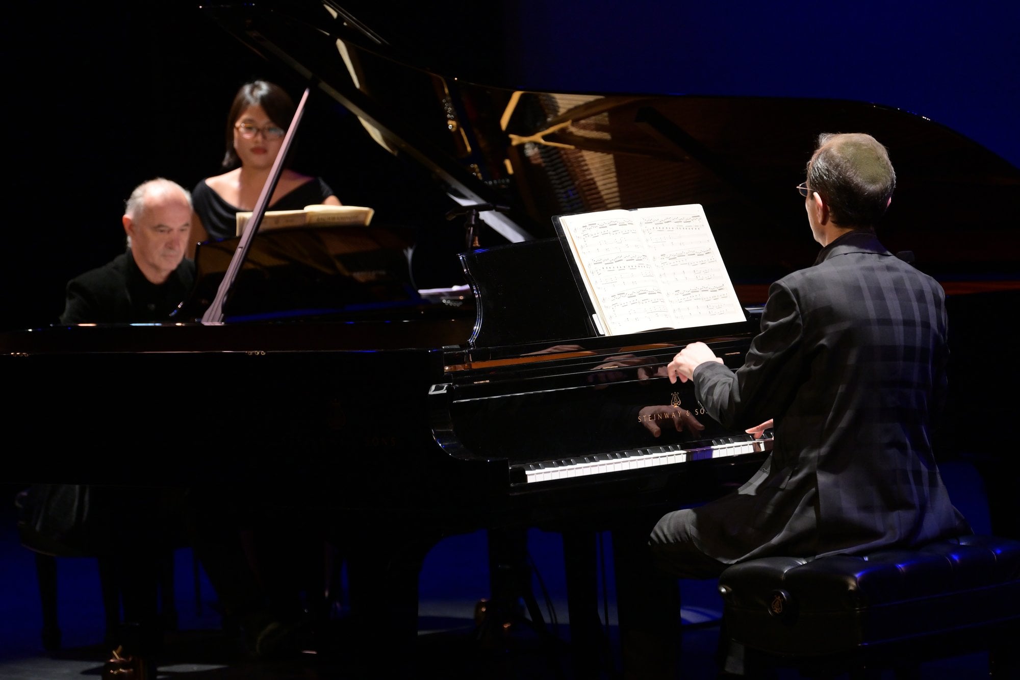 Two pianists at the keyboard, with their page turner